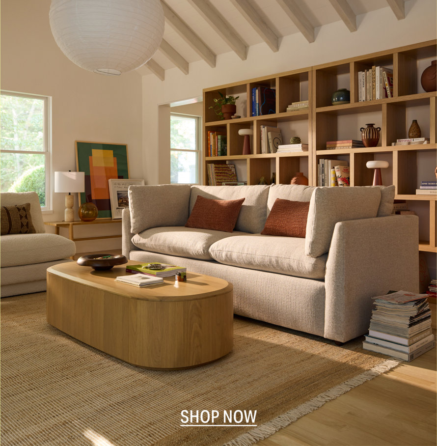 Living room with a boucle sofa, oval wood coffee table and styled bookshelf