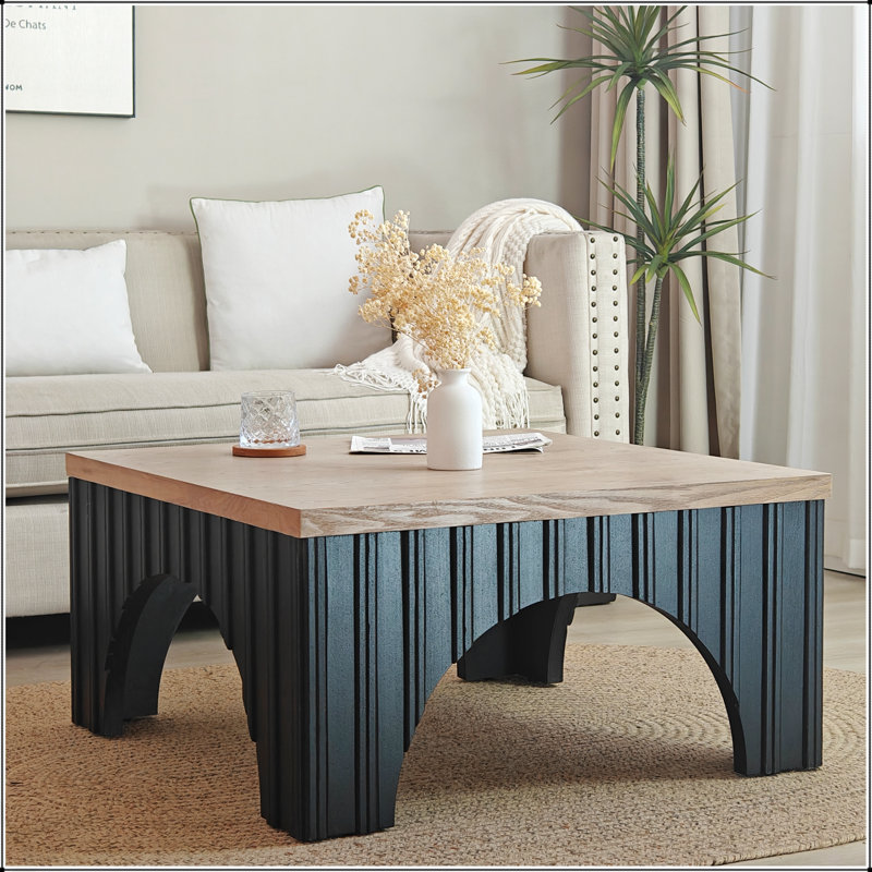 Table basse rustique carrée avec plateau épais et base arquée, alliant style campagnard moderne et durabilité