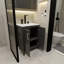 Une armoire de salle de bain noire de 24 pouces, jumelée à un lavabo en céramique blanche, présente un design moderne et est faite de matériaux imperméables et durables