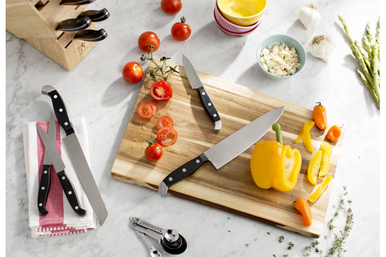 Several types of knives posed on a cutting board with vegetables