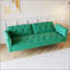 Luxueux canapé-lit en velours vert avec garniture cloutée et coussin décoratif assorti pour un confort élégant