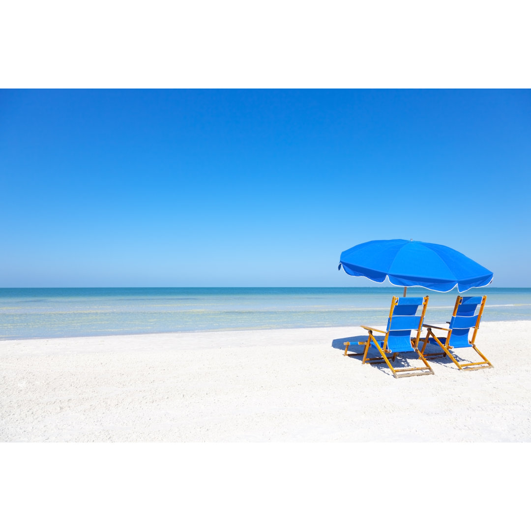 Liegestühle und Sonnenschirm am Strand von Bertlmann - Leinwandbild