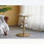 Luxueuse table d'appoint ronde en fer avec accents floraux dorés et blancs, base en ciment robuste pour une décoration intérieure élégante