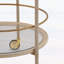 Chariot-bar rond avec tablettes en verre trempé et accents dorés, finition blanche vieillie, idéal pour les décors modernes et rétro