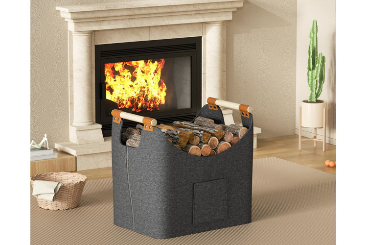 gray fabric basket with firewood inside next to a white woven basket all on a rug in front of a fireplace.
