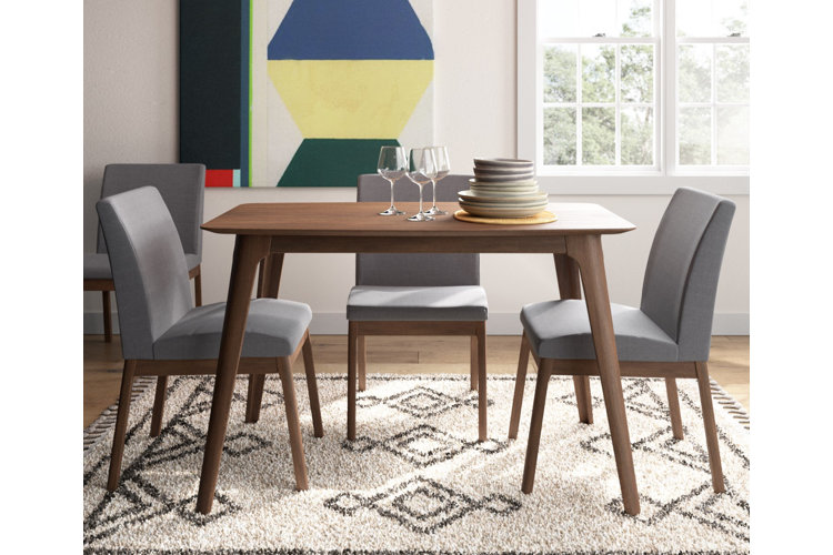 Modern dining room idea with a streamlined wood table and gray upholstered chairs on top of a patterned rug.