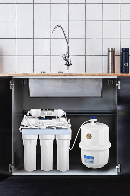 Système de filtration d'eau par osmose inverse sous évier avec cartouches filtrantes blanches et réservoir de stockage sous pression installé sous le robinet d'un évier de cuisine.