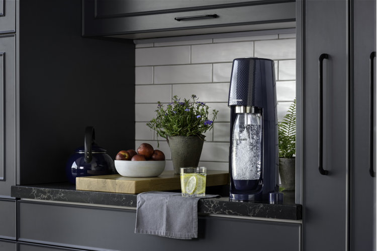 Dark blue cabinets and black marble countertop with a soda maker with homemade sparkling water