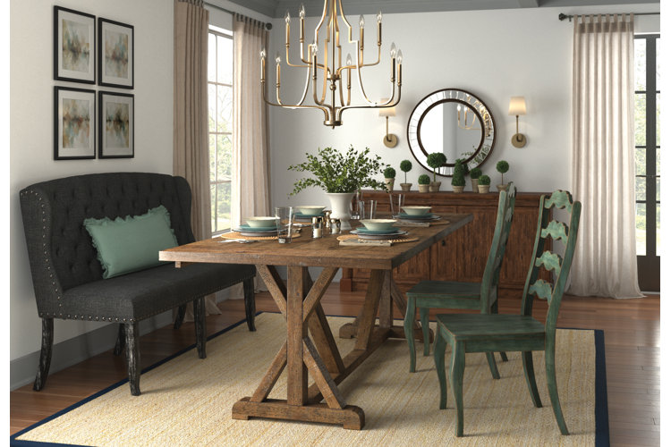 rustic dining room with a wood trestle table, and black leather banquette seating beneath a gold chandelier