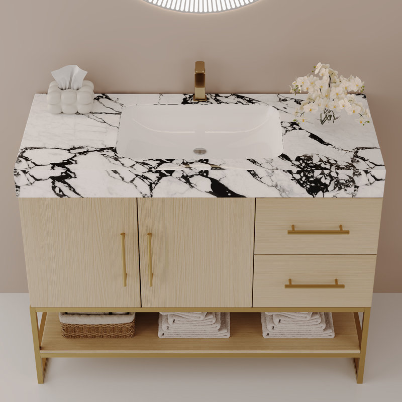 Meuble-lavabo autoportant moderne de 91 cm (36 po) avec comptoir en pierre frittée, lavabo en céramique intégré, armoire en chêne clair, structure en acier inoxydable doré, tiroirs fermés et tablette de rangement ouverte pour salle de bain résidentielle.