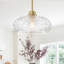 Suspension moderne en laiton naturel à une lumière avec abat-jour en verre transparent texturé diamant, tige réglable, idéale pour un îlot de cuisine ou un hall d'entrée.