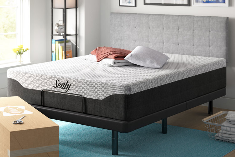 mattress on a metal bed frame ith a gray upholstered headboard