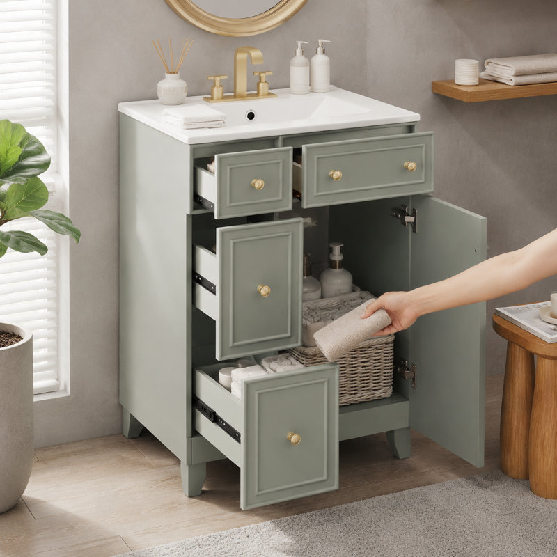 Meuble-lavabo sur pied vert sauge avec quincaillerie dorée et lavabo blanc