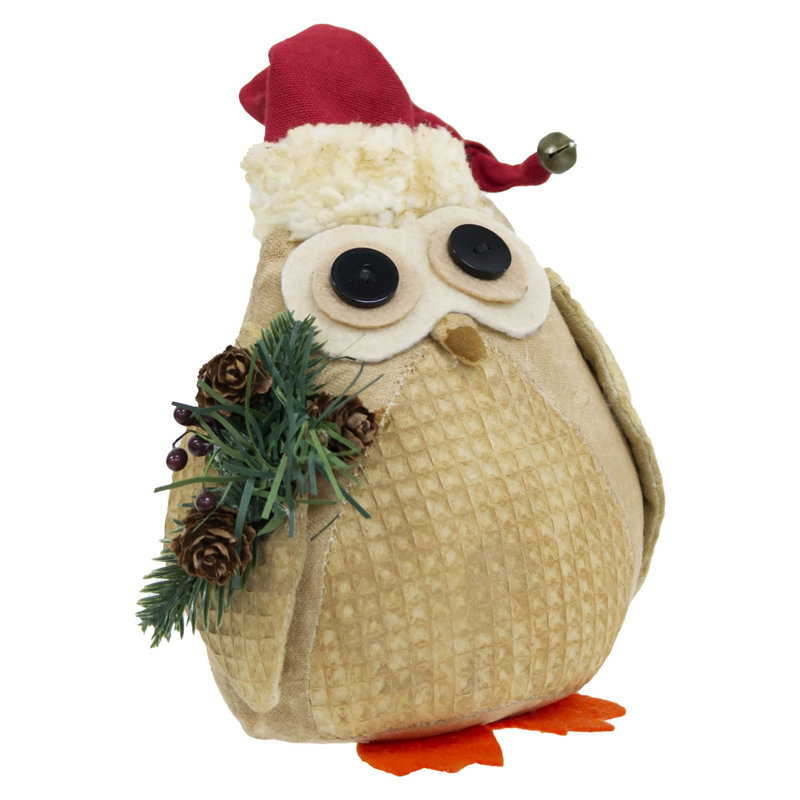 Hibou en peluche avec chapeau de père Noël et verdure hivernale