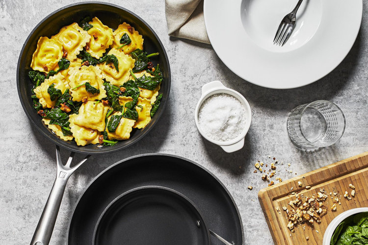 gray hard-anondized three-piece nonstick frying pan set with ravioli and spinach