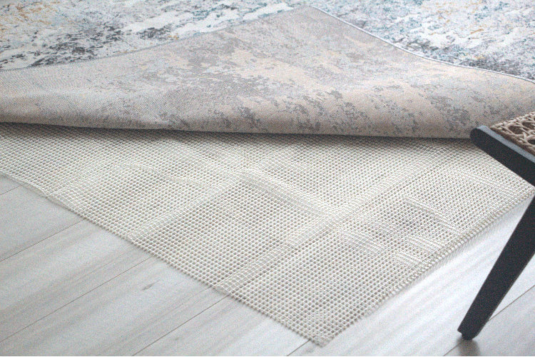 flat-weave rug folded up at the corner exposing a rubber rug pad