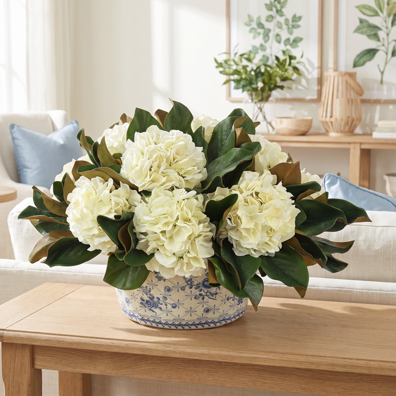 Hortensias et feuilles de magnolia disposés dans un vase décoratif