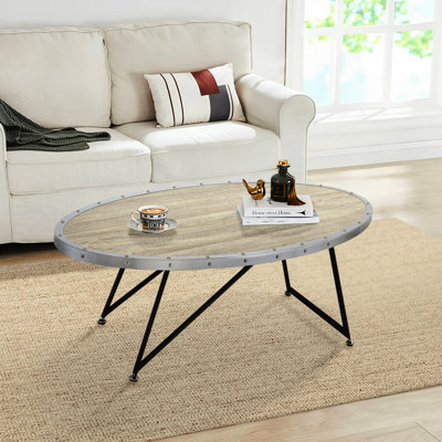 Table basse ovale de style industriel avec finition en chêne gris patiné et supports en métal noir pour une grande surface