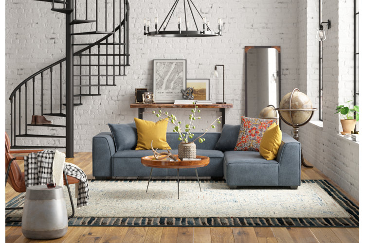 industrial boho living room with a slate gray sectional, layered area rugs, and a wagon wheel chandelier