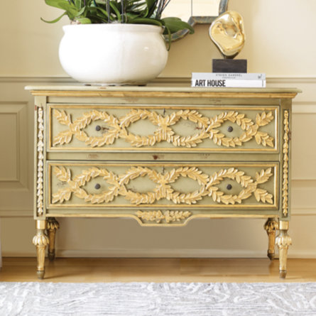 Orchid arrangement on a leaf motif chest with book.