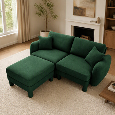 Canapé d'angle 2 places en tissu bouclé, avec accoudoirs originaux en forme de coquillage et pouf amovible, pieds cylindriques recouverts du même tissu, coloris vert.