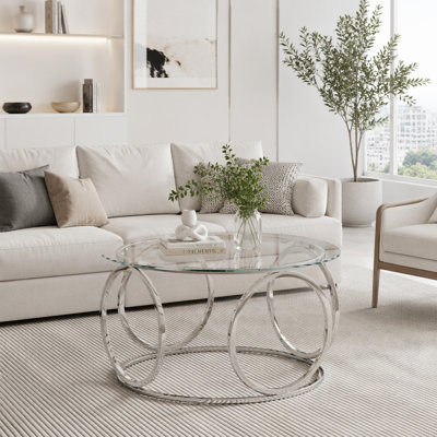 Table basse moderne avec plateau rond en verre et structure circulaire en métal