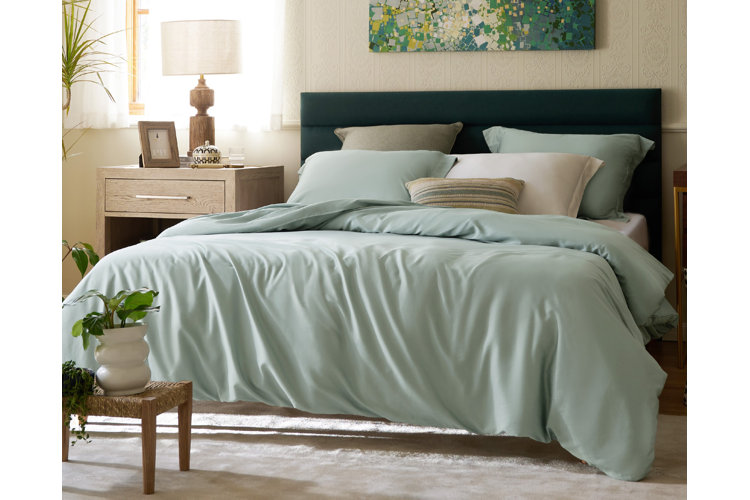 green bedding with pillow, sheet, and fitted sheet on a bed with a deep green headboard
