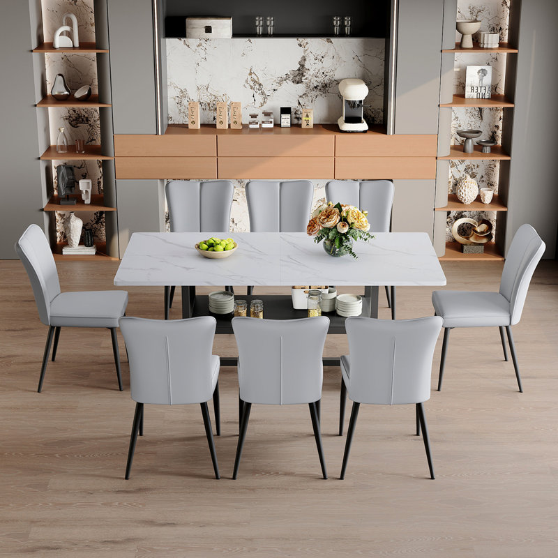 Ensemble de table et de chaises Table de salle à manger 71 * 35,4 pouces à grain blanc épissé avec fonction de rangement au milieu des pieds. Combinée avec 8 chaises en polyuréthane gris clair avec un motif à rayures verticales sur le dossier.