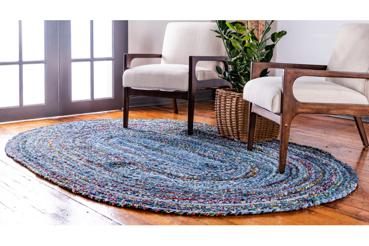 multicolor braided rug in a living room with cream chairs