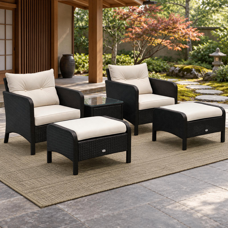 Ensemble de conversation cinq pièces en osier tressé, inspiré du style côtier, avec coussins, poufs et table basse en verre, idéal pour les patios et les jardins.