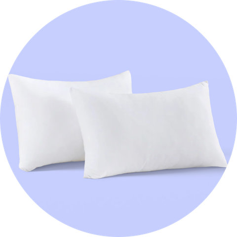 Deux oreillers de lit blancs présentés sur un fond circulaire violet.