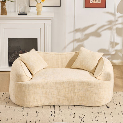 Beige curved two - person compress sofa. It has armrests on both sides, comes with two pillows, is suitable for small - sized apartments, and can be placed in the living room or bedroom.