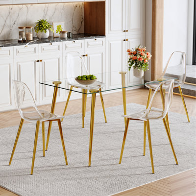 Ensemble de table et de chaises. Ensemble de table de salle à manger moderne et luxueux en verre trempé rectangulaire avec 4 chaises en plastique transparent avec pieds en métal doré. Apportez une expérience de maison confortable à la cuisine.