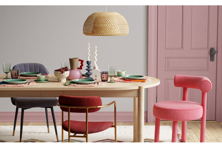 Modern dining room with mismatched dining chairs around a light wood oval-shaped table beneath a rattan chandelier.