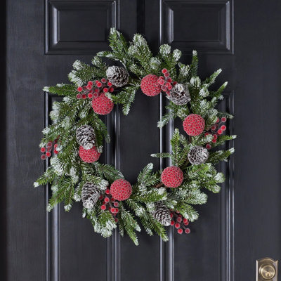Couronne de manteau de Noël enneigée en pin, boule de baies rouges glacées et pomme de pin