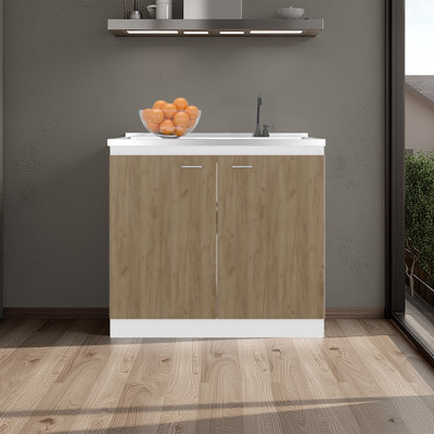 Évier utilitaire Napoles avec robinet intégré et comptoir en acier intégré, armoire autoportante avec deux portes, poignées en métal et deux tablettes intérieures.
