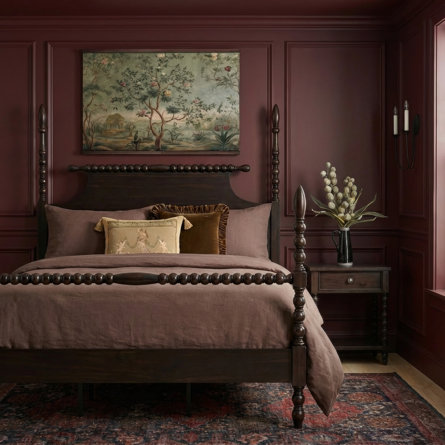 Victorian gothic style bedroom featuring deep mauve walls, a dark wood spindle bed frame, chinoiserie artwork on the wall, and moody atmospheric lighting creating an elegant, dramatic ambiance
