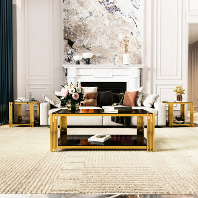 Ensemble de 3 tables pour salon : 1 table basse rectangulaire et 2 tables d'appoint. Plateau en verre trempé, structure asymétrique en métal doré, tablettes du bas pour magazines. Collection au style moderne. Forme rectangulaire.