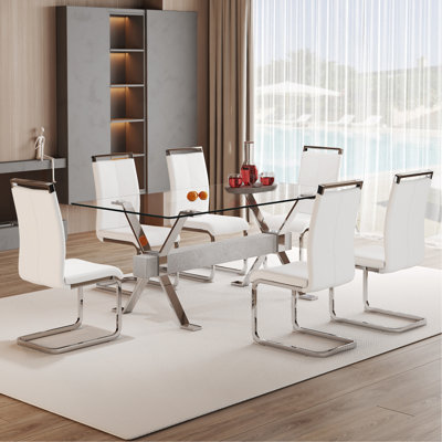 Ensemble de table et de chaises. Ensemble de salle à manger élégant en verre trempé transparent - 71 po x 35,4 po avec 6 chaises en polyuréthane blanc avec pieds en métal en forme de C en argent. Pieds de table en métal argentés en forme de X, traverse en bois aggloméré texturé gris.