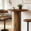 Table de bar ronde rustique en bois aggloméré industriel avec anneau repose-pieds en métal et colonne en faux grain de bois, pour bar, restaurant ou salon à la maison
