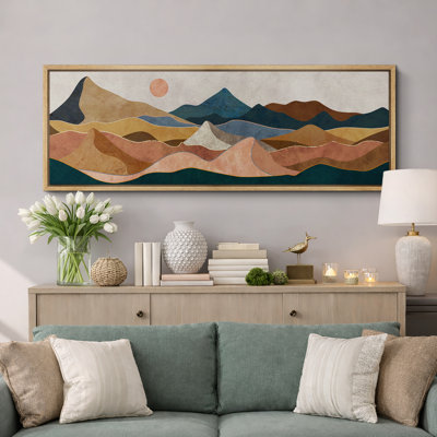 Panoramic framed wall art featuring an abstract desert mountain landscape in earthy tones of brown, blue, and tan.