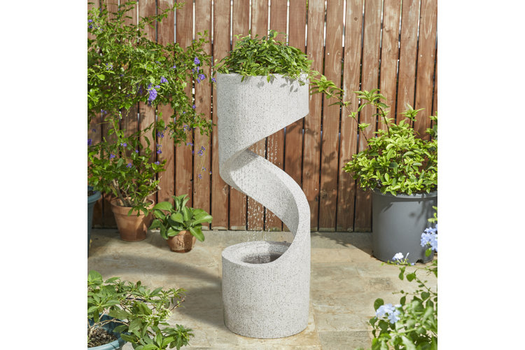 Backyard fountain idea with a spiral-shaped column fountain with a planter on top and water cascading down the center.