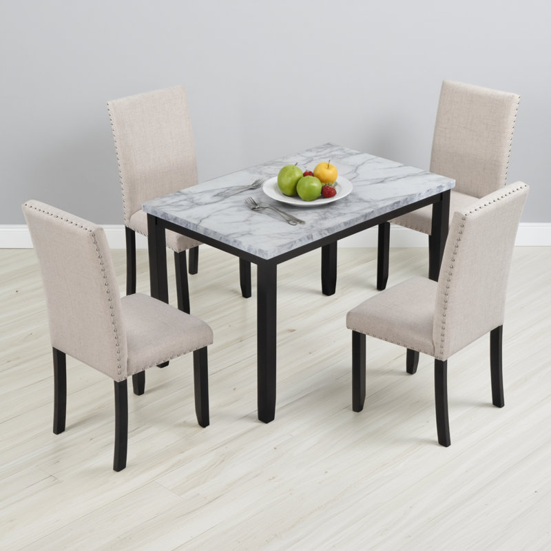 Un ensemble de table de salle à manger en imitation marbre 5 pièces avec 4 chaises de salle à manger rembourrées moelleuses dans un agencement blanc / beige et noir contrastant pour compléter n'importe quelle maison.