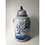Vase en porcelaine bleue et blanche avec toujours des fleurs vertes et prunes