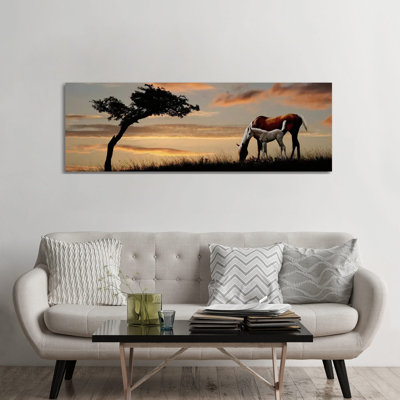 Horse Mare And A Foal Grazing By Tree At Sunset - Wrapped Canvas Panoramic Print
