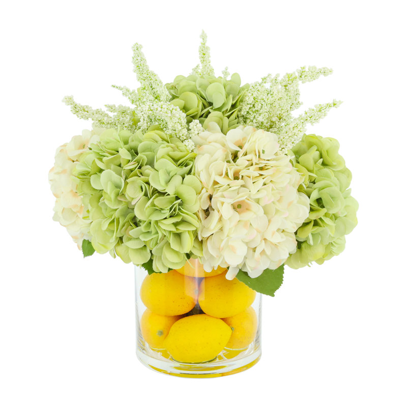 Hortensias disposés dans un vase en verre avec des citrons