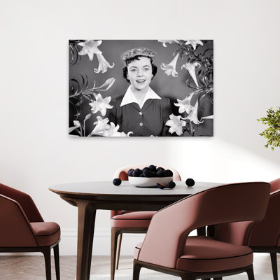 Portrait des années 1950, femme brune souriante portant un bonnet de Pâques regardant la caméra entourée de lys de Pâques