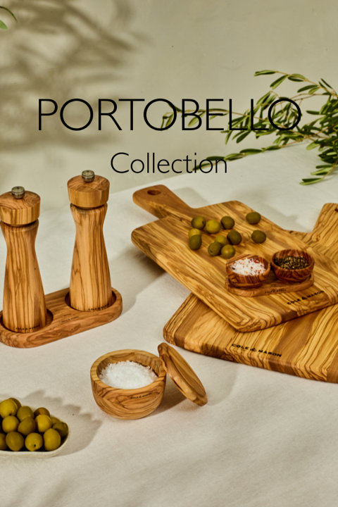 Portobello Collection olive wood kitchenware including salt and pepper mills, serving boards, and small spice bowls on a white tablecloth.