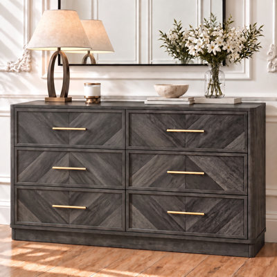 Commode moderne à 6 tiroirs de 140 cm de large, avec façades de tiroirs à motif en chevron et poignées dorées.
