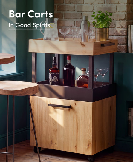 Bar Carts: In Good Spirits, featuring a modern wooden bar cart with a cabinet and metal accents in a room with a brick wall.